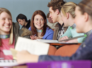 Captured Girls Gone Wild in a simulated classroom setting, where tracking collars that emit a slight shock are used to curb the girls' instinct to jump up on desks and remove their tops.